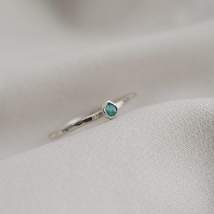 May include: A silver ring with a small, teardrop-shaped green opal gemstone.