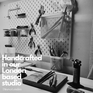 May include: Black and white photo of a workshop with tools hanging on a pegboard. The text "Handcrafted in our London based studio" is visible in the image.  The text "Dinoval London" is also visible in the image.