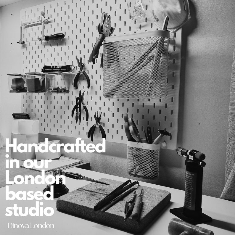 May include: Black and white photo of a workshop with tools hanging on a pegboard. The text "Handcrafted in our London based studio" is visible in the image.  The text "Dinoval London" is also visible in the image.