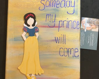 May include: A yellow and blue canvas painting with a paper cutout of Snow White. The text "Someday my prince will come" is written in purple glitter on the canvas.