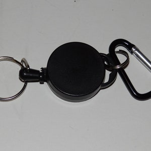 May include: A black retractable key chain with a silver carabiner clip and a round black key ring.
