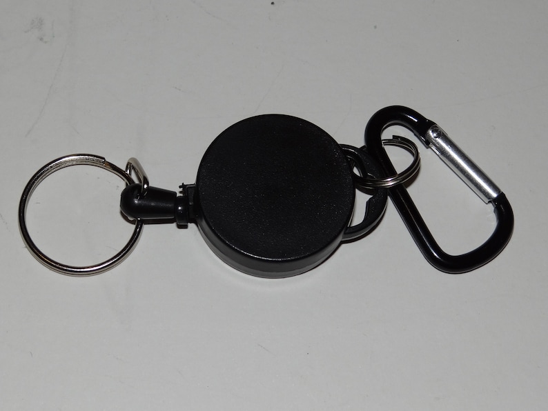 May include: A black retractable key chain with a silver carabiner clip and a round black key ring.