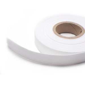 May include: A roll of white cotton bias tape, a type of fabric trim used for finishing edges of garments and other sewing projects.