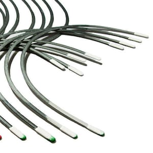 May include: A close-up of a bundle of thin, silver-colored metal wires with white and green tips. The wires are arranged in a fan shape, with the tips pointing towards the right side of the image.