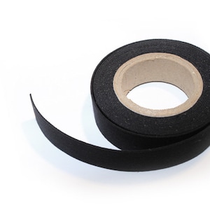 May include: A roll of black fabric tape with a cardboard core. The tape is rolled up and a section is unrolled, showing the black fabric.