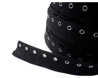 May include: Black fabric trim with silver grommets. The trim is rolled up and a section is unrolled to show the grommets.