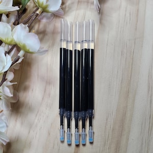 May include: Five black ink refills for pens. The refills are clear plastic with black ink inside. The refills have blue tips.