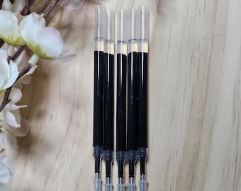 May include: Five black ink refills for pens. The refills are clear plastic with black ink inside. The refills have blue tips.
