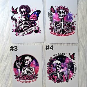 May include: Four white cards with skeleton illustrations. Each card features a skeleton with floral and butterfly accents, set against a galaxy-themed background. The phrase "MY LAST FLYING FUCK" is included on each card.