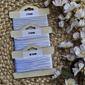 May include: Three spools of white thread in cardboard packaging. The spools are labeled with the text "3 Yards", "5 Yards", and "10 Yards".