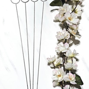 May include: Four silver metal floral wire rings with long stems. The rings are about 1 inch in diameter. The stems are about 10 inches long.