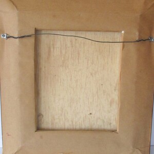 Puede incluir: La parte posterior de un cuadro enmarcado con un marco de madera marr&oacute;n y un alambre de suspensi&oacute;n sujeto a la parte superior.