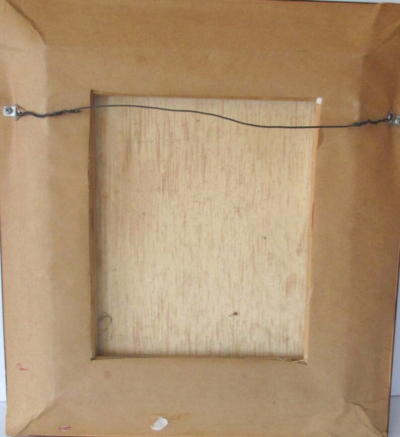 Puede incluir: La parte posterior de un cuadro enmarcado con un marco de madera marr&oacute;n y un alambre de suspensi&oacute;n sujeto a la parte superior.