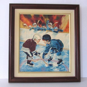 Puede incluir: Una pintura enmarcada de dos j&oacute;venes jugadores de hockey enfrent&aacute;ndose en el hielo. El jugador de la izquierda lleva una camiseta granate y el jugador de la derecha lleva una camiseta azul. Ambos jugadores llevan cascos y sujetan palos de hockey. El fondo muestra a un grupo de otros j&oacute;venes jugadores de hockey viendo el partido.