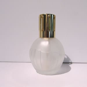 Peut inclure: Un brûleur à huile en verre givré avec un couvercle en métal doré et un motif décoratif. Le couvercle comporte une série de petits trous pour libérer le parfum.