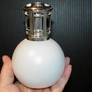 Peut inclure: Un diffuseur d'huiles essentielles en verre givré blanc avec un dessus en métal argenté et un design de cage décoratif.