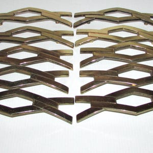May include: Fourteen gold-coloured metal decorative hardware pieces. Each piece features a geometric, openwork design with diamond shapes and curved bars. The hardware is arranged in two neat rows on a white surface.