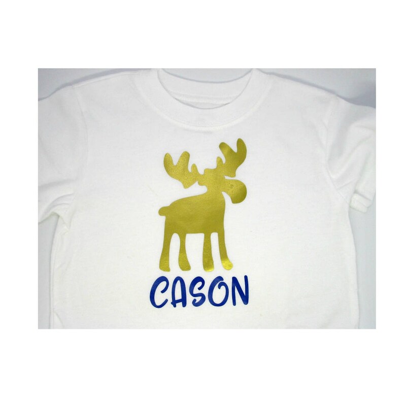 May include: White t-shirt with a gold moose silhouette and the name "CASON" in blue lettering.