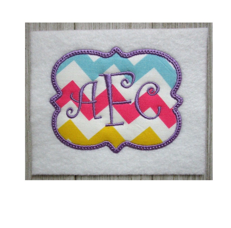 May include: Purple embroidered monogram "AFC" in a decorative frame with a chevron pattern in pink, yellow, blue and white.