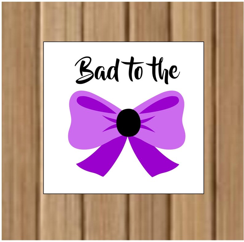 May include: A white square with the text "Bad to the" in black lettering and a purple bow with a black center.