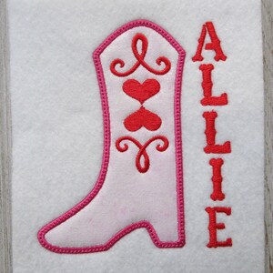 May include: Embroidered design of a pink cowboy boot with red hearts and swirls, and the name "ALLIE" in red lettering.