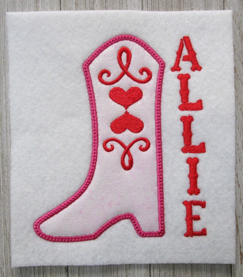 May include: Embroidered design of a pink cowboy boot with red hearts and swirls, and the name "ALLIE" in red lettering.