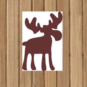 May include: A brown moose silhouette cut out from white paper. The moose has large antlers and a long snout.