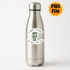 Puede incluir: Una botella de agua de acero inoxidable con una pegatina que presenta una rana de dibujos animados verde con un sombrero de vaquero y un peto. La pegatina tiene el texto "I have a feelin' Your Okies Ain't Dokie."