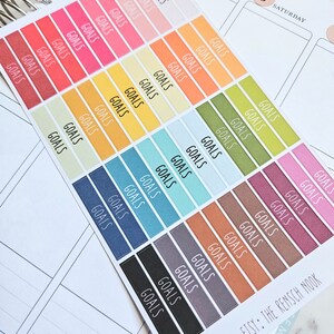 Puede incluir: Una hoja de pegatinas coloridas con la palabra "GOALS" impresa en cada pegatina. Las pegatinas est&aacute;n dispuestas en filas y columnas, con cada fila presentando un color diferente. Las pegatinas est&aacute;n dise&ntilde;adas para su uso en una agenda o diario.