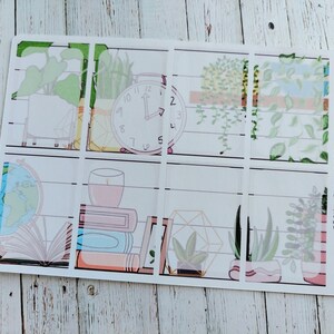 May include: A set of 9 clear planner stickers featuring a white wood plank background with various illustrations of plants, a clock, books, and a globe. The text "ETSY: THE RENSCH NOOK" is printed on the right side of the sticker sheet.