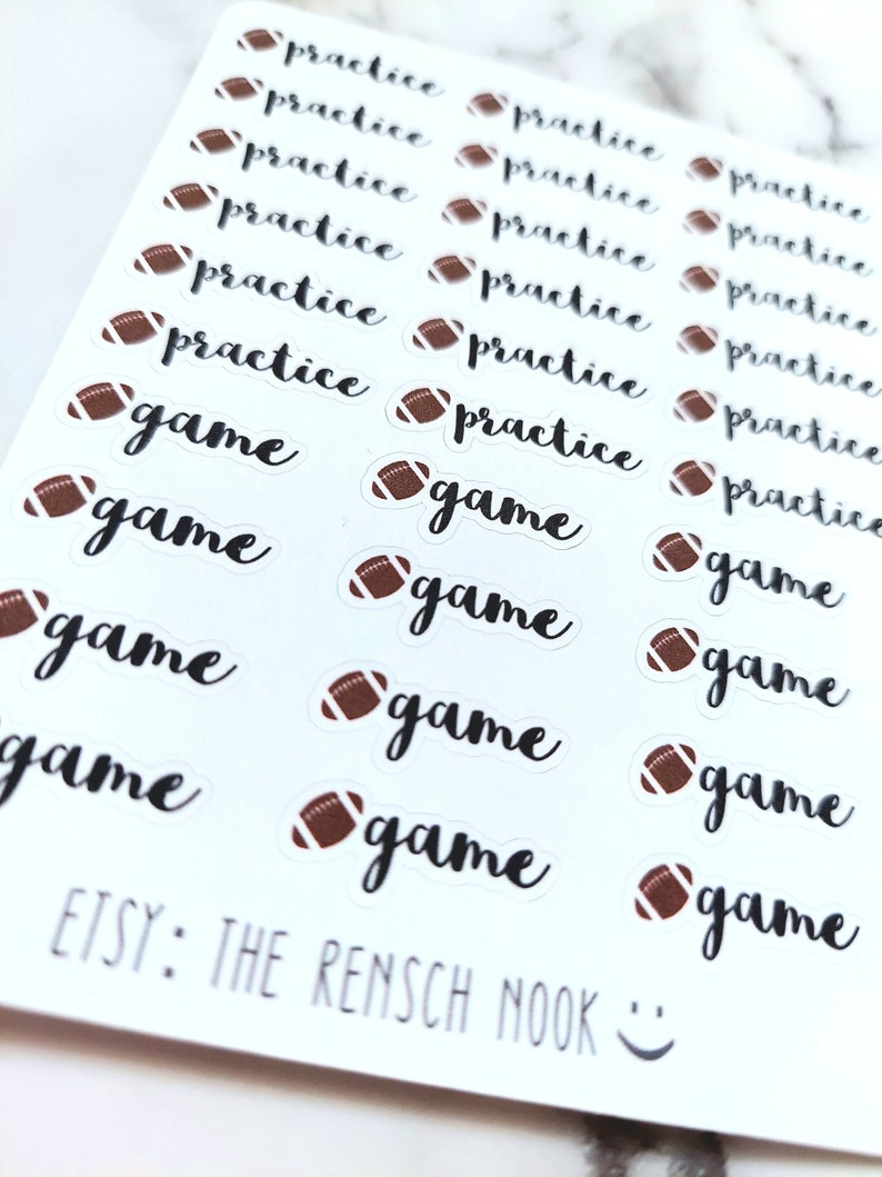 May include: A sheet of white stickers with brown football illustrations. The stickers have the words "practice" and "game" written in black cursive.