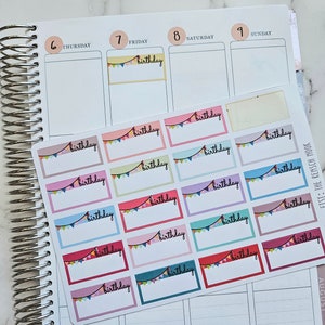 May include: A planner with a spiral binding, open to a weekly view. A sheet of colorful birthday stickers with the word "birthday" and a banner design is on top of the planner.