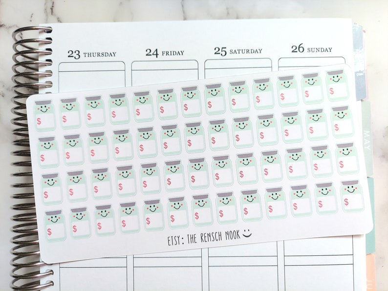 May include: Sheet of planner stickers featuring smiling jar illustrations with dollar signs. The stickers are light green with gray lids and pink dollar signs. The sheet is on a planner page with the text "ETSY: THE RENSCH MOOK".