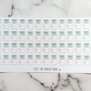 May include: Sheet of stickers featuring smiling jars with dollar signs and blank labels. The jars are light green with gray lids and happy faces. The text "ETSY: THE REMSCH MOOK" is at the bottom.