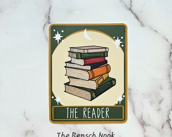 May include: A green and gold sticker with a stack of books and a crescent moon. The text "THE READER" is printed on the sticker. The text "The Rensch Nook" is printed below the sticker.