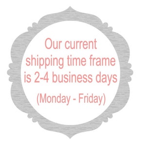 May include: A gray and white decorative sign with a pink text overlay. The text reads "Our current shipping time frame is 2-4 business days (Monday - Friday)"