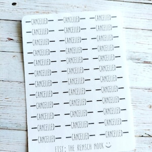 May include: A sheet of white stickers with the word "CANCELLED" printed in black, repeated in rows and columns. The text "ETSY: THE RENSCH NOOK" is printed at the bottom. The stickers are on a light wood grain surface.