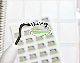 Puede incluir: Una hoja de pegatinas para planificador con un sofá verde con cojines coloridos y la palabra "therapy" en escritura negra. Las pegatinas están sujetas por una herramienta blanca y negra, sobre una página de planificador blanca.