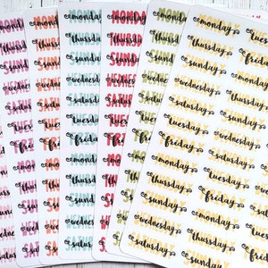 May include: A sheet of colorful stickers with the days of the week written on them. The stickers are in various colors, including pink, orange, blue, green, and yellow. The days of the week are written in a handwritten style font.