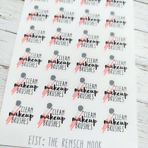 May include: Sheet of stickers with the text "CLEAN makeup BRUSHES" in black script, accompanied by a pink and gray makeup brush illustration. The Etsy shop name "ETSY: THE RENSCH NOOK" is printed at the bottom.