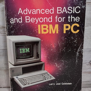 May include: A softcover book titled Advanced BASIC and Beyond for the IBM PC by Larry Joel Goldstein. The cover features a space-themed background with a gradient of red and black, displaying a vintage beige IBM computer and keyboard.