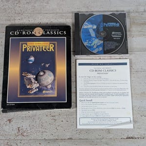 May include: A Wing Commander Privateer CD-ROM Classics game set including a black cardboard box with space-themed cover art, a clear plastic jewel case containing a game disc with blue and black graphics, and a white paper quick install guide.
