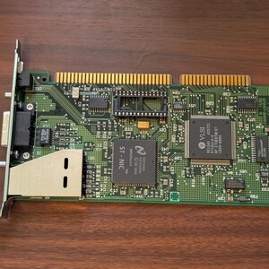 May include: A green printed circuit board network interface card featuring a metal bracket, gold-plated edge connector pins, and various integrated circuit chips including a VLSI chip and an ST-NIC chip with visible text markings and circuitry.