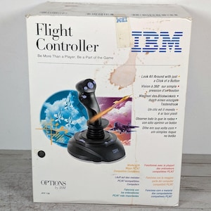 May include: A white cardboard box for an IBM Flight Controller joystick. The box features the IBM logo, the text Flight Controller, and a graphic of a black joystick with a rocket. It includes multi-language text and technical specifications.