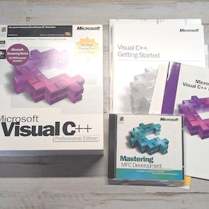 May include: A Microsoft Visual C++ Professional Edition software package including a large box, a Getting Started manual, a Visual C++ Directory book, and a Mastering MFC Development CD-ROM case. The items feature purple and teal block graphics.