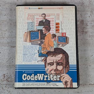 May include: A rectangular software box for the Commodore 64 titled CodeWriter. The cover features a large illustration of a man's face, a smaller scene of people working at computers, and text describing the plain language program system.