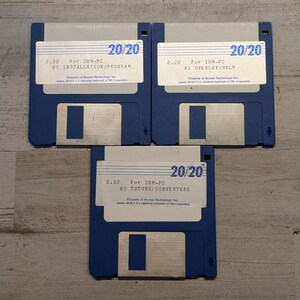 May include: Three blue 3.5-inch floppy disks labeled 20/20 version 2.22 for IBM-PC. The labels are numbered #1 Installation/Program, #2 Overlay/Help, and #3 Tutors/Converters. Each disk features a silver metal sliding shutter and white label.