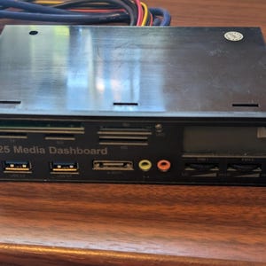 May include: A black 5.25 Media Dashboard computer component featuring multiple card reader slots, two USB 3.0 ports, an e-SATA port, audio jacks, a small digital display screen, and two fan speed control dials with attached multi-colored wiring cables.