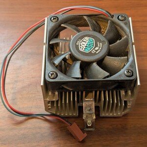 May include: A square Cooler Master computer cooling fan with black blades and a silver aluminum heat sink. The fan features a central label with the text Cooler Master, Ball, and Made in China. A red and black wire with a brown connector is attached.