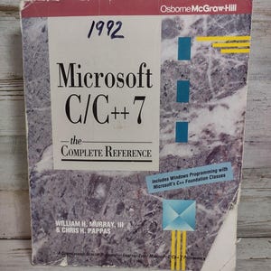 May include: A softcover technical book titled Microsoft C/C++ 7 The Complete Reference by William H. Murray, III and Chris H. Pappas. The cover features a purple marble pattern, blue geometric accents, yellow lines, and the handwritten year 1992.